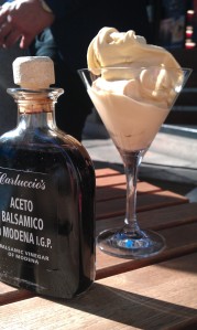 A martini glass with gelato piled in, with a bottle of balsamic vinegar beside.